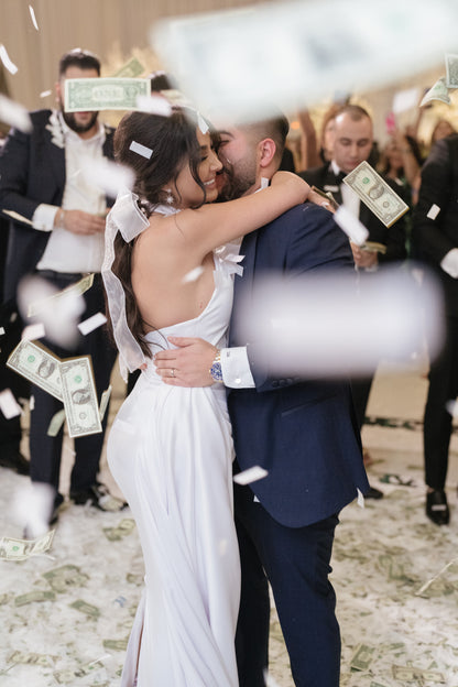 bride and groom dancing amid confetti with bow in hair