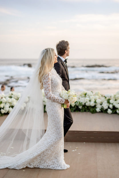 romantic sheer two tier cascade cut long bridal veil as bride and groom walk along beach