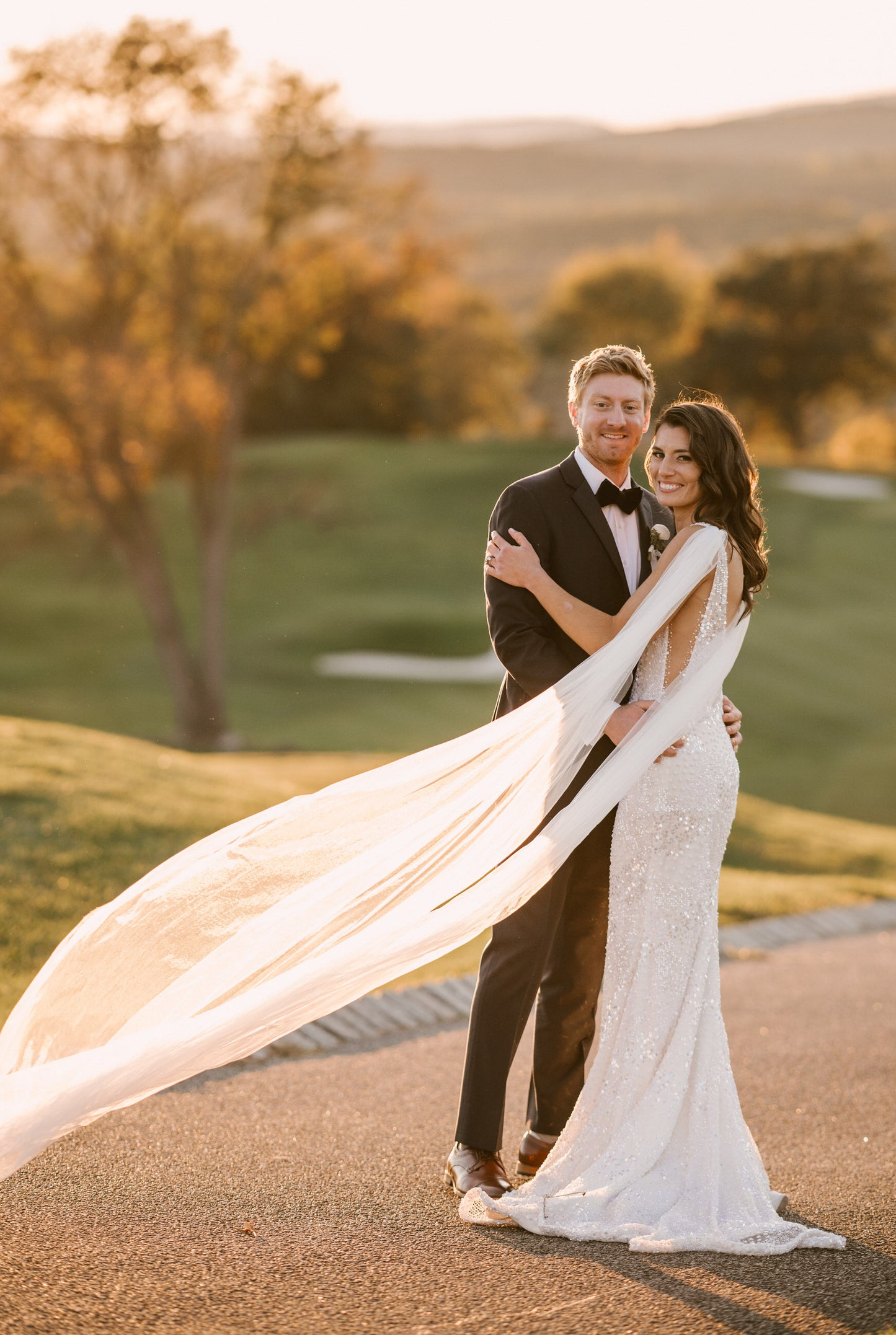 outdoor golf course wedding with bride wearing romantic long cathedral length light ivory bridal wing set  and beaded side cutout wedding dress 