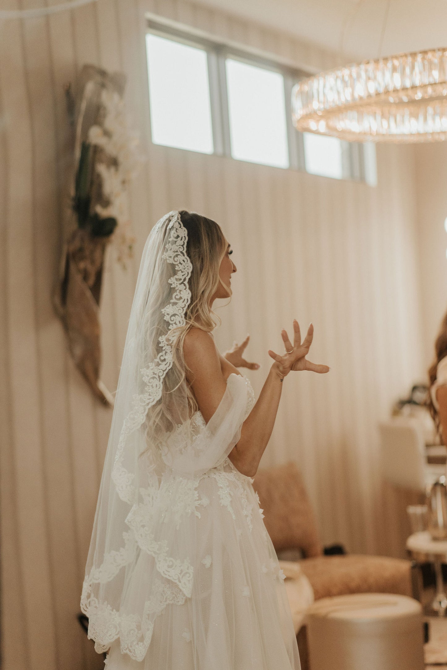 bride in off the shoulder flowy blush wedding dress with light ivory fingertip length mantilla bridal veil on top o f head