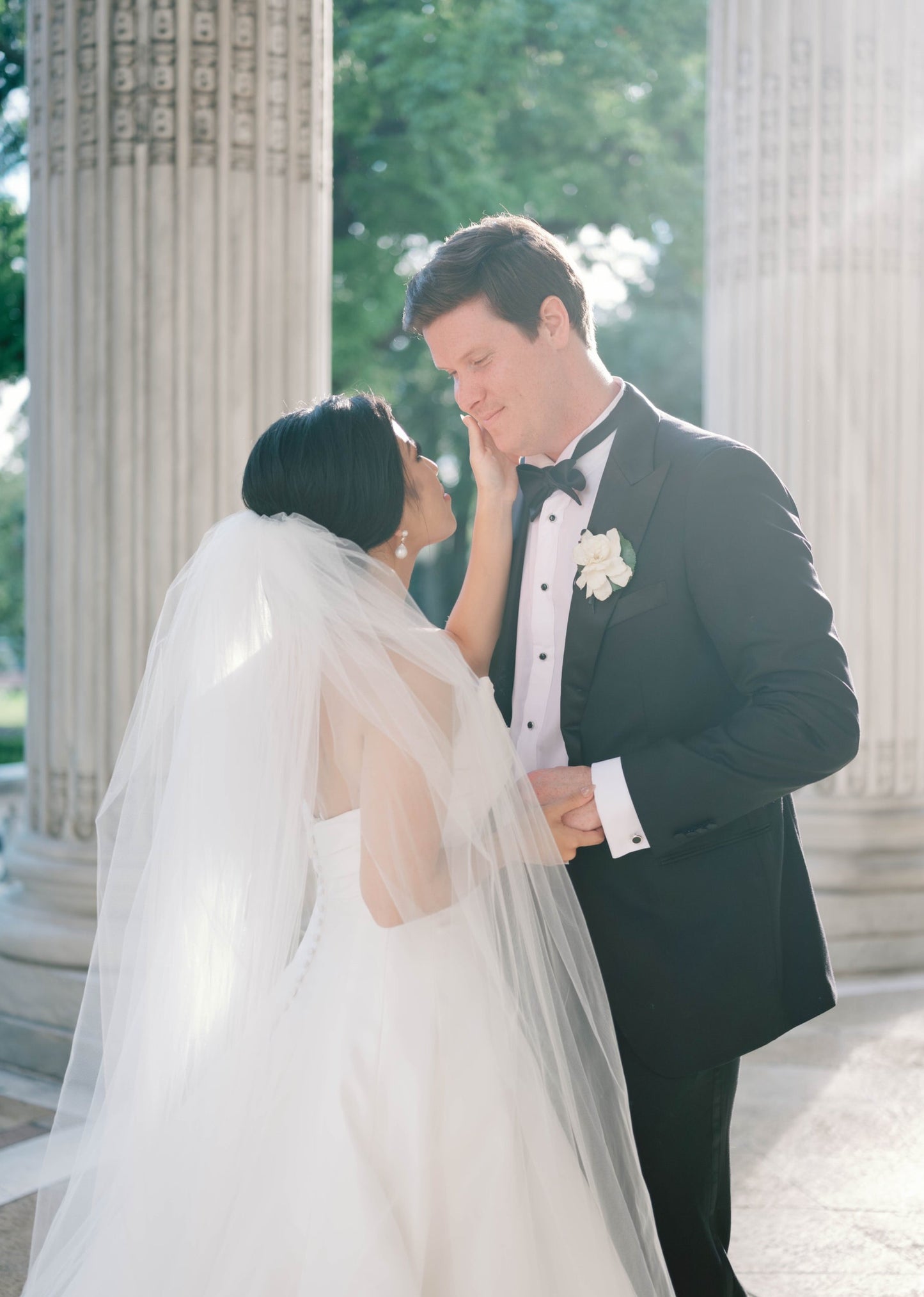 large puffy royal length puffy bridal veil over low chignon in bride's hair as she holds groom's face