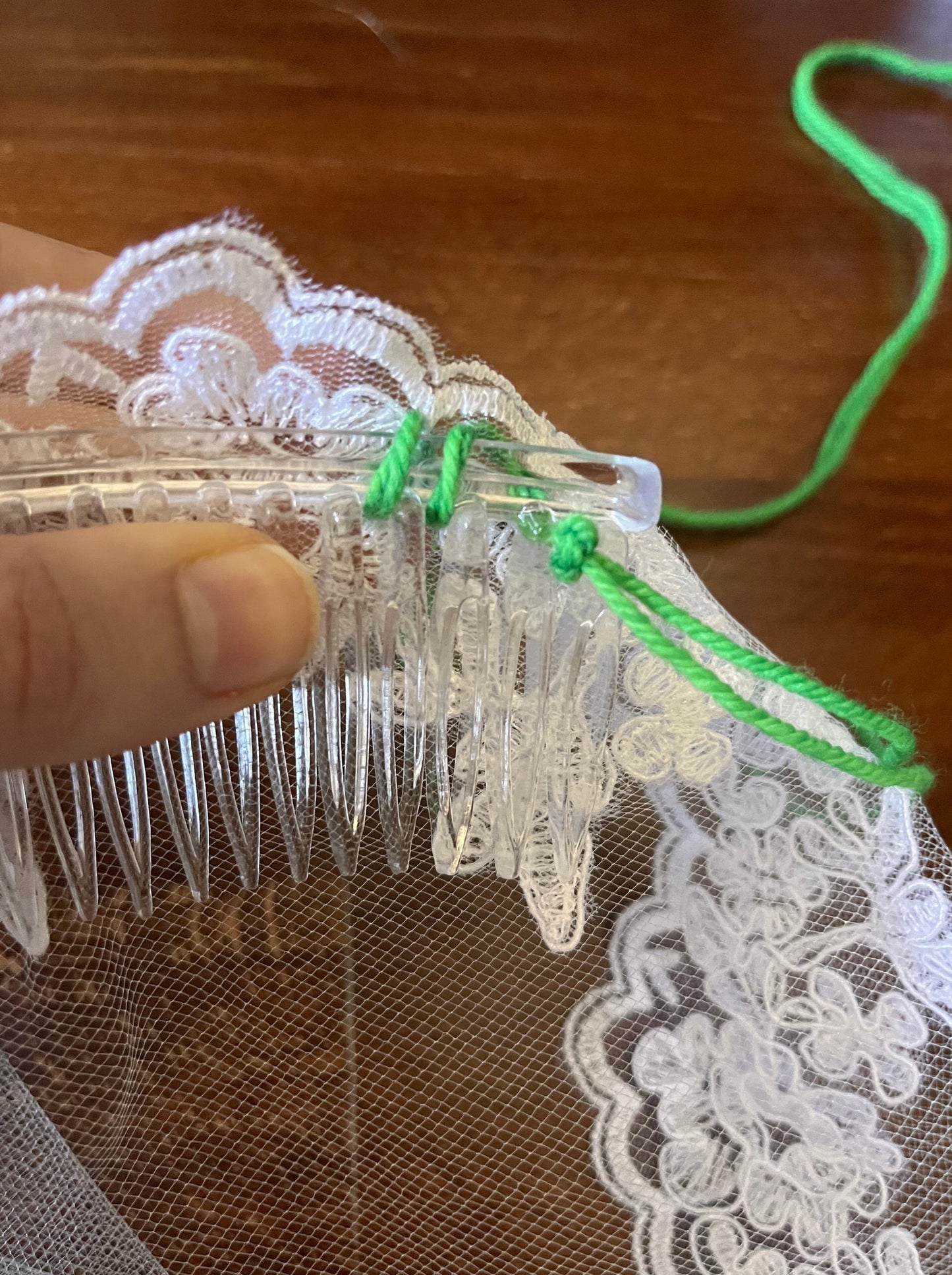 sewing the clear comb to the lace edge of the communion veil 