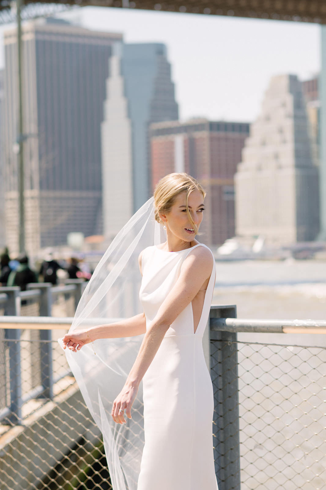 elegant soft silk tulle bridal veil in low updo and crepe gown with side cutouts and cityscape background