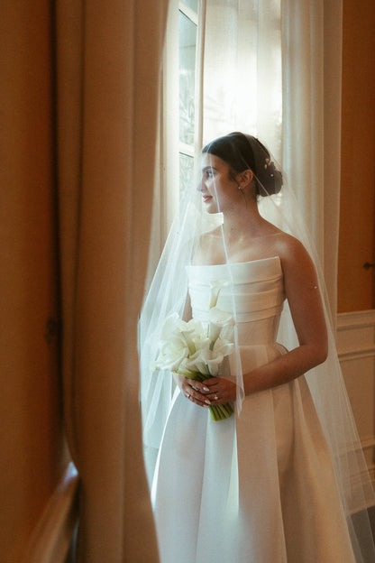 low updo on bride with pearl hair pins and two layer cathedral length wedding veil with raw edge