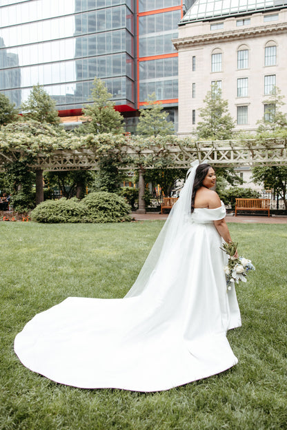 detachable bridal hair bow for wedding paired with long cathedral length wedding veil and ballgown on lawn outside hotel